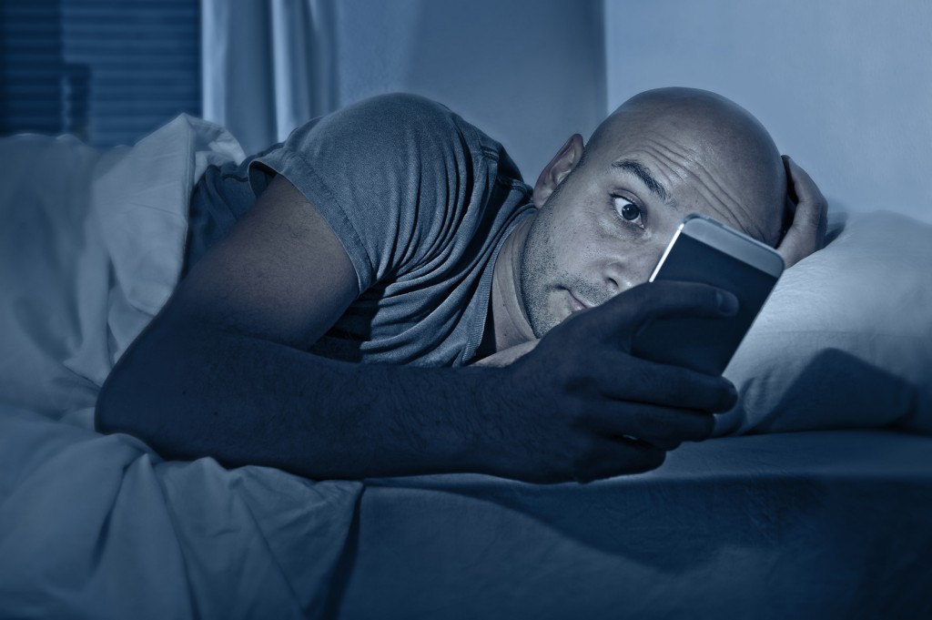internet addict man awake at night in bed with mobile phone