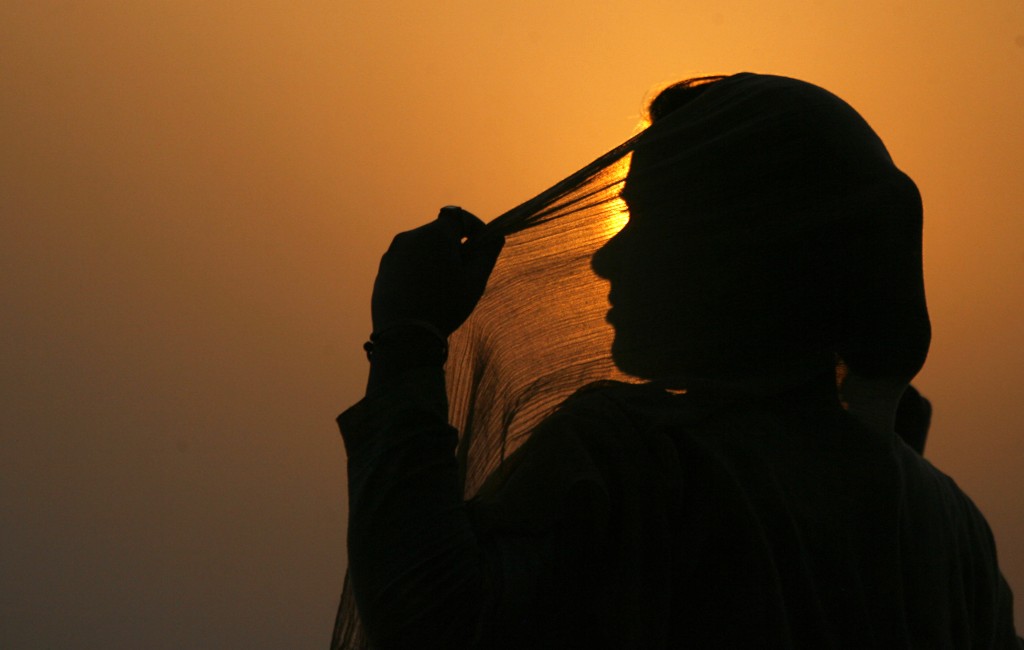 A woman adjusts her scarf as the sun sets over Kashmir's Dal Lake in Srinagar