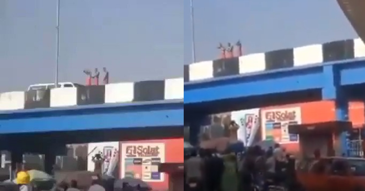 Three people clad in only red wrapper are seen bathing on a bridge in Ibadan (video)