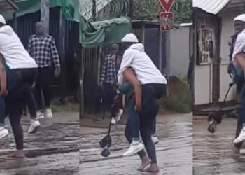 “The guy fit be last born” – Reactions as lady backs her man to cross flooded road (Video)