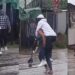 “The guy fit be last born” – Reactions as lady backs her man to cross flooded road (Video)