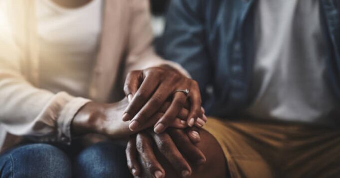 Cropped shot of a man and woman sitting on a sofa and holding hands